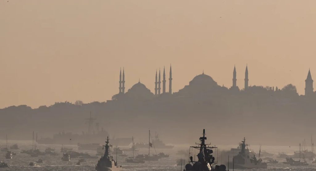 A hazy silhouette of Istanbul’s skyline, including mosques, overlooking ships in the harbor at sunset.