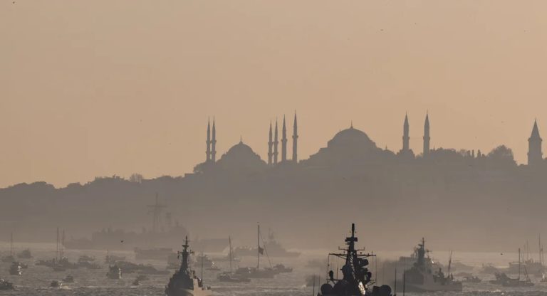A hazy silhouette of Istanbul’s skyline, including mosques, overlooking ships in the harbor at sunset.