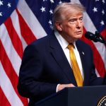 Former President Donald Trump speaking at a podium with American flags in the background.