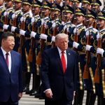 Donald Trump walking alongside a Chinese official past a military honor guard.