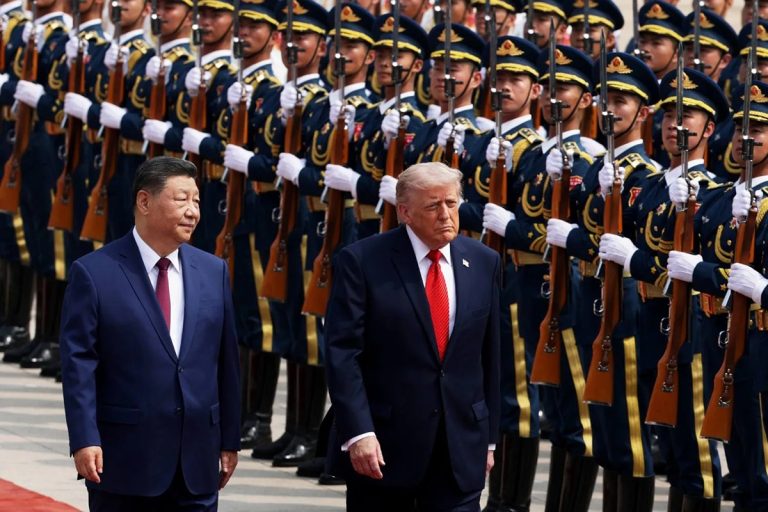 Donald Trump walking alongside a Chinese official past a military honor guard.