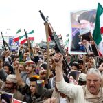 Protesters in Yemen holding rifles and posters.
