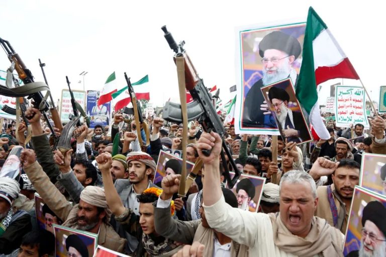 Protesters in Yemen holding rifles and posters.
