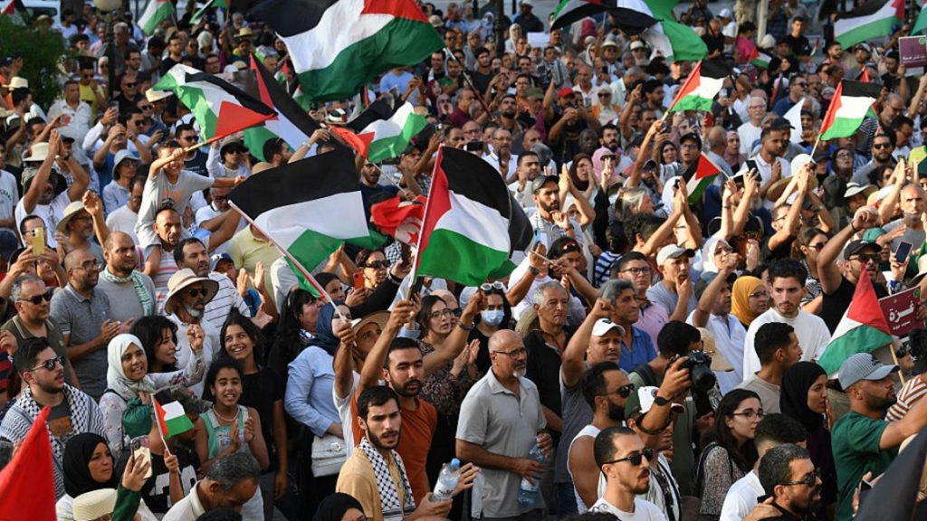 Crowds waving Palestinian flags during a public demonstration protesting regional normalisation policies.
