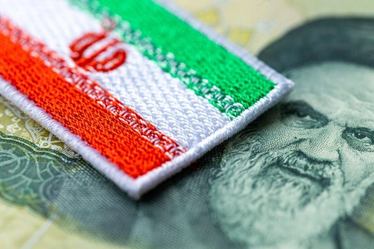 Iranian flag emblem patch placed over Iranian Rial currency banknote