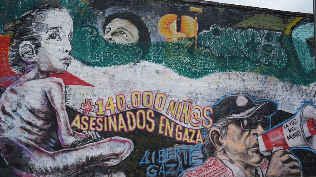 Urban street mural depicting political activism and protest slogans regarding Gaza.