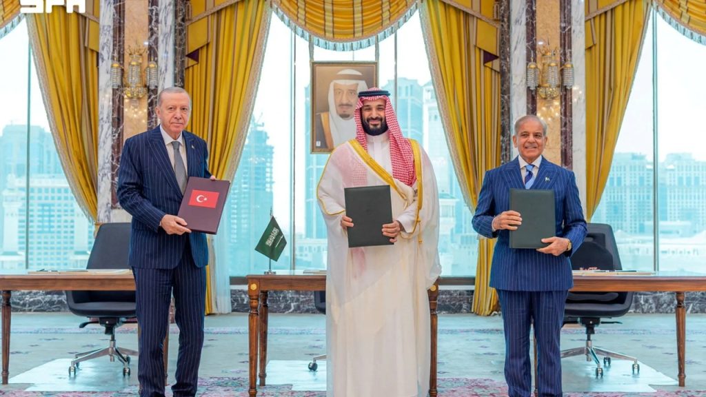 Turkish President Recep Tayyip Erdogan, Saudi Crown Prince Mohammed bin Salman, and Pakistani Prime Minister holding agreement folders indoors.
