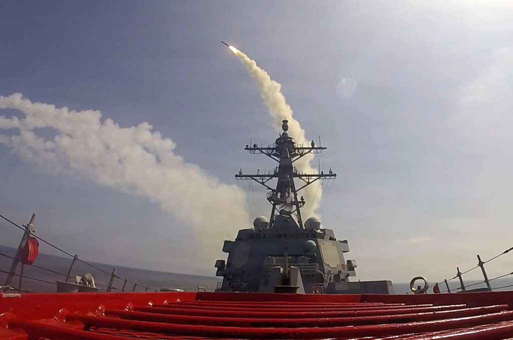 Guided missile launching from the deck of a naval destroyer creating a trail of smoke in the sky.