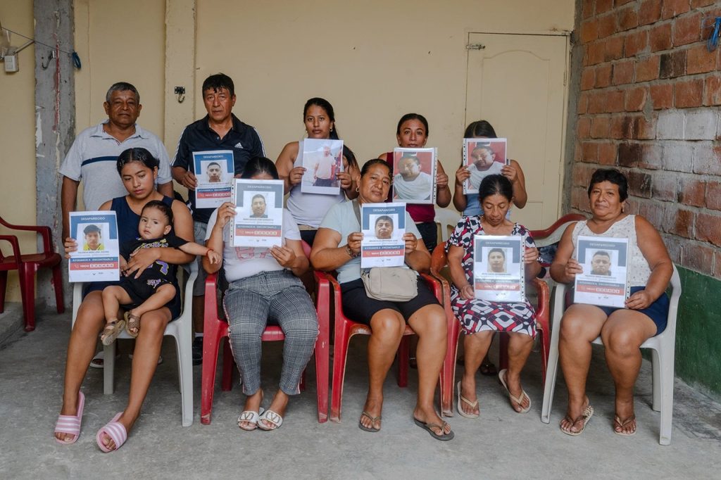 Family members holding up framed photographs of missing individuals during a press gathering.