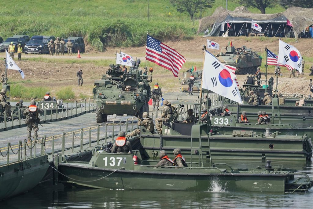 Joint military vehicles and amphibious assault boats participating in allied defense exercises.