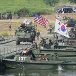 Joint military vehicles and amphibious assault boats participating in allied defense exercises.