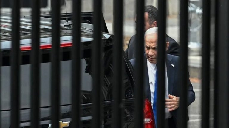Israeli Prime Minister Benjamin Netanyahu walking behind black fence bars