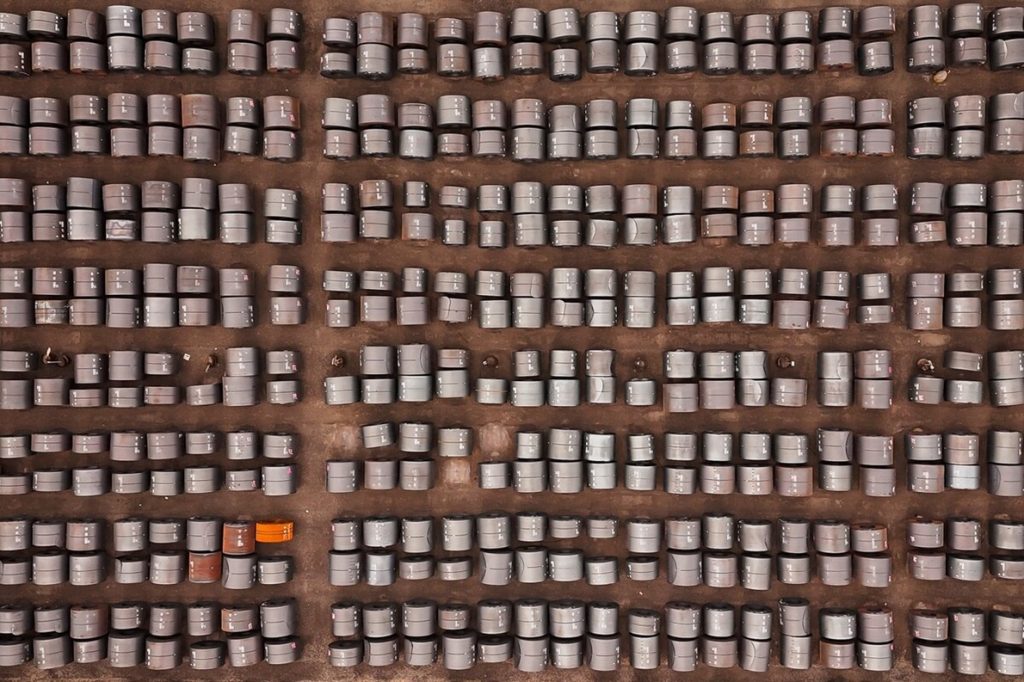Top-down aerial view of thousands of rolled steel coils stored outdoors in an industrial yard.