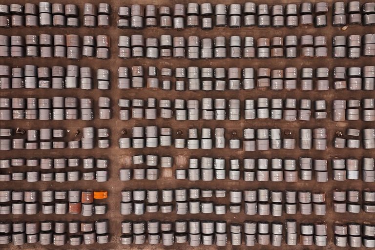 Top-down aerial view of thousands of rolled steel coils stored outdoors in an industrial yard.