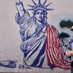 Woman walking past a street mural of the Statue of Liberty in Tehran.