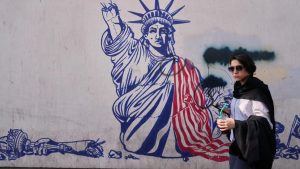 Woman walking past a street mural of the Statue of Liberty in Tehran.