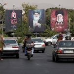 Street traffic in Tehran with large political billboards displaying Ayatollah Ali Khamenei