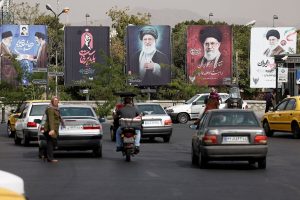 Street traffic in Tehran with large political billboards displaying Ayatollah Ali Khamenei