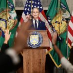 U.S. official speaking at a Department of the Treasury podium surrounded by American flags.