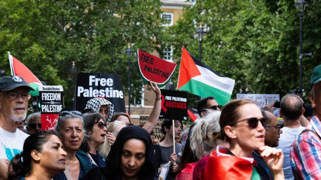Protesters holding Palestinian flags and placards at a demonstration in London.
