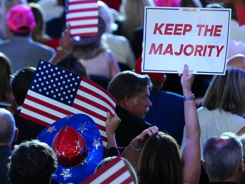 Supporter holding a Keep the Majority sign and American flags in a rally crowd