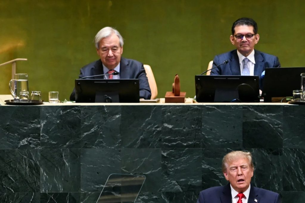 Donald Trump speaking at the UN podium below seated United Nations officials.