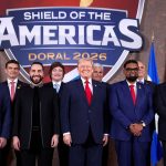 Donald Trump standing with Latin American and regional leaders under the Shield of the Americas banner