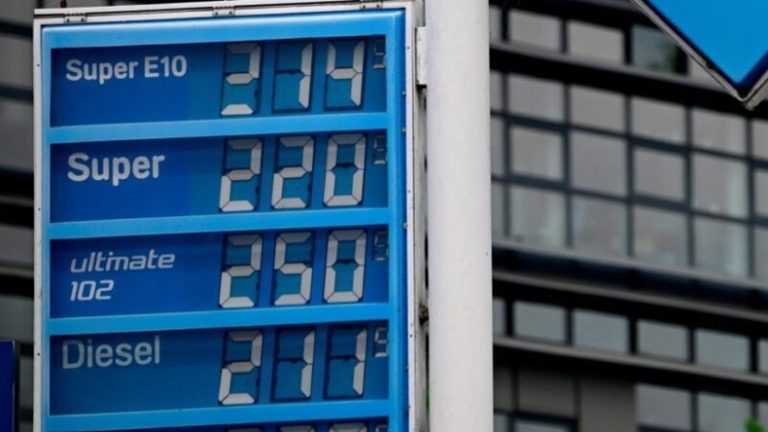 A fuel price display board showing high prices for Super E10, Super, Ultimate 102, and Diesel.