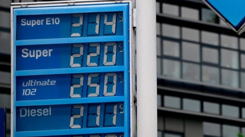 A fuel price display board showing high prices for Super E10, Super, Ultimate 102, and Diesel.