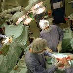 Surgeons in full protective gowns performing an operation in an operating room.