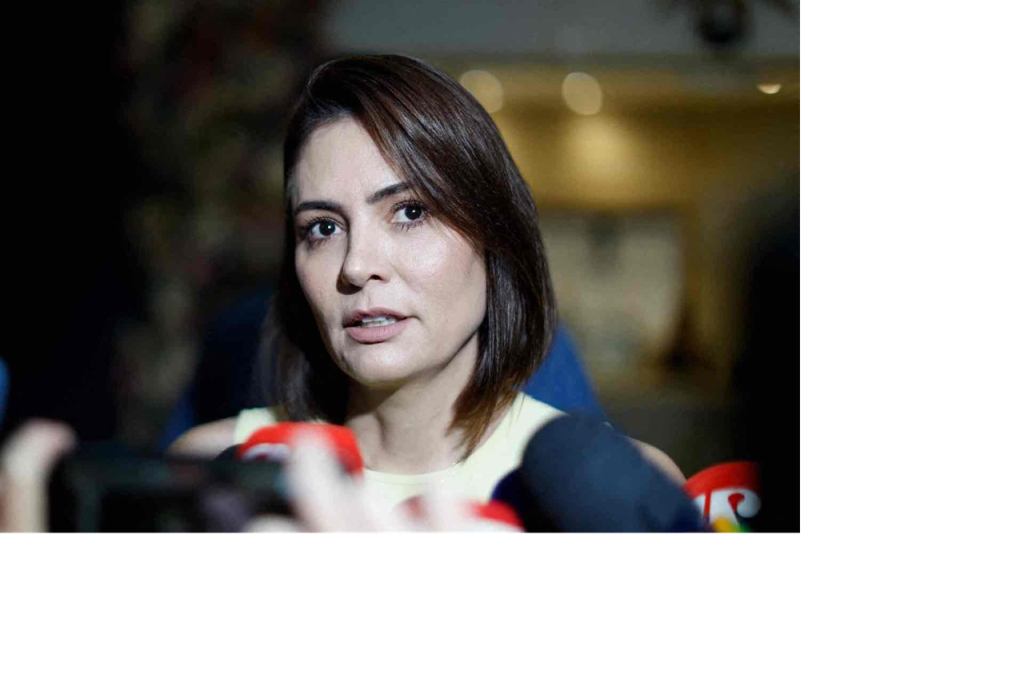 Close-up portrait of Michelle Bolsonaro speaking into microphones at a press conference.