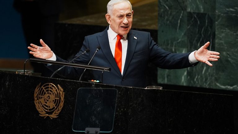 Israeli Prime Minister Benjamin Netanyahu gesturing with both hands while speaking at the United Nations General Assembly lectern.