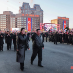 Kim Jong Un and his daughter walking through a crowd during a public event in North Korea.