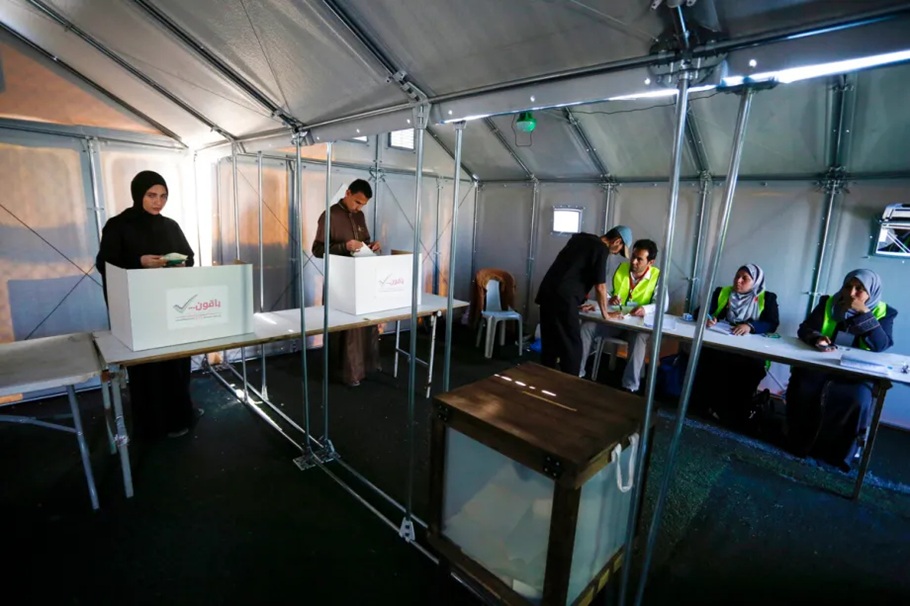 Voters casting ballots in cardboard voting booths set up inside a temporary tent polling place.