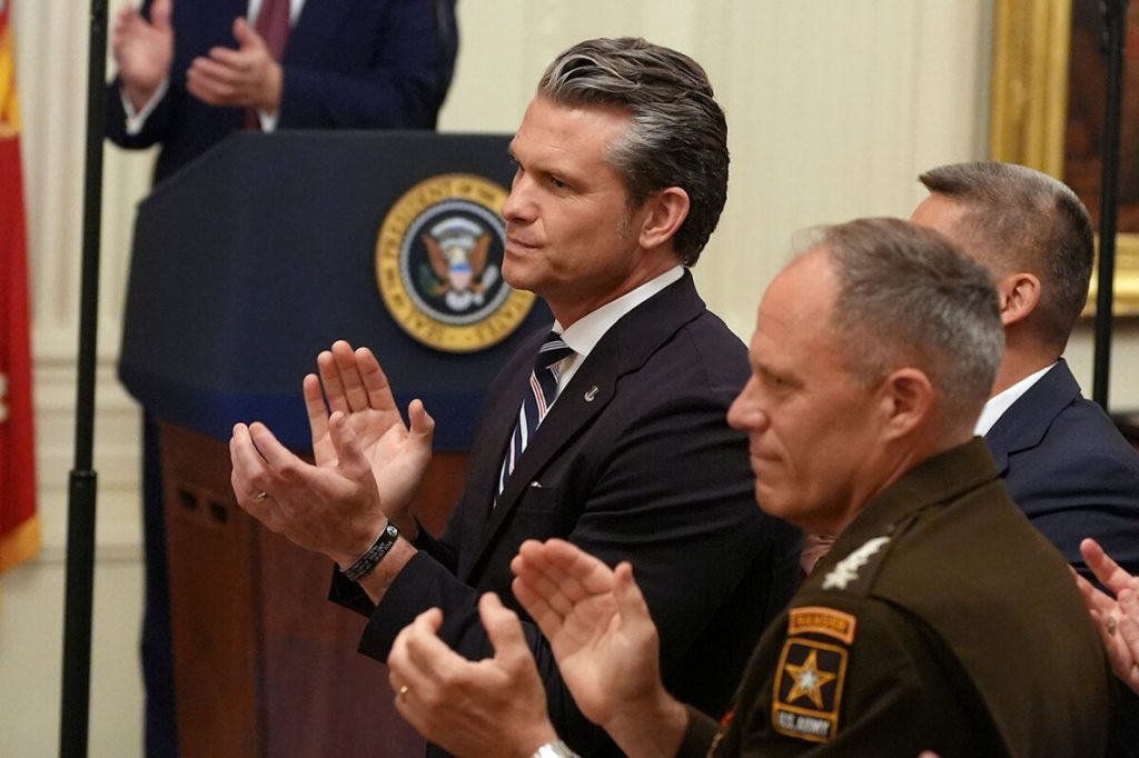 Pete Hegseth clapping alongside military officials during a formal event.