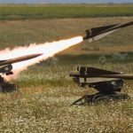 Surface-to-air missile launchers firing missiles in a field.