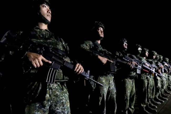 Taiwanese military soldiers standing in formation holding rifles during a nighttime exercise.