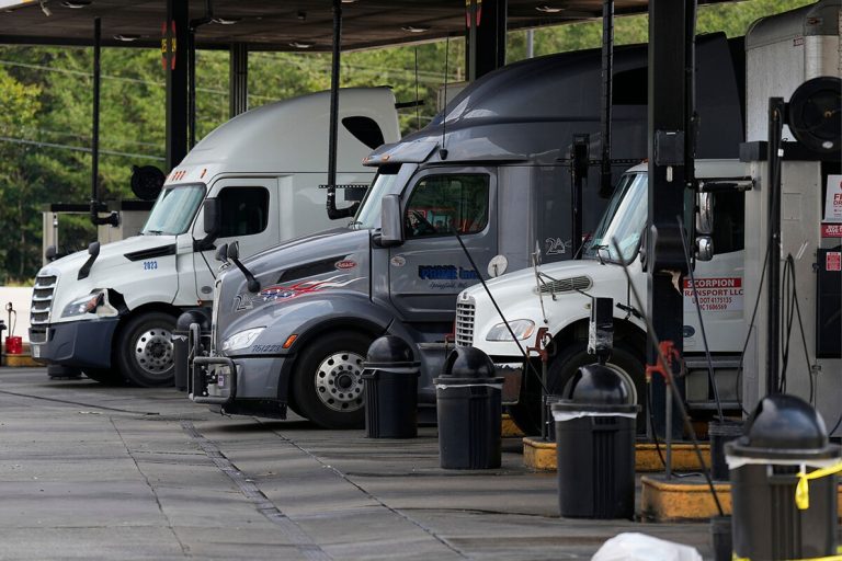 Semi-trucks parked at commercial diesel fuel pumps at a truck stop.
