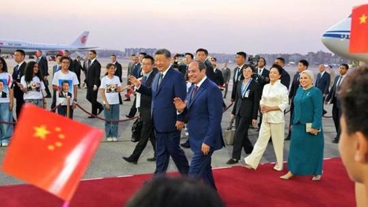 Chinese President Xi Jinping and Egyptian President Abdel Fattah el-Sisi walking together on a red carpet at an airport runway.
