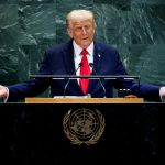 Donald Trump gesturing with open arms at the UN podium.