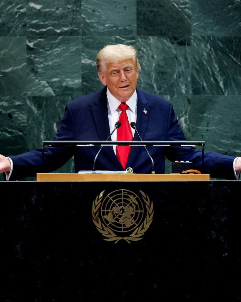 Donald Trump gesturing with open arms at the UN podium.