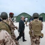 UN Secretary-General António Guterres walking past armed international security personnel at a field site.