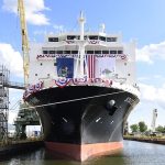 Large maritime training and cargo ship docked in a dry dock facility draped with American flags.