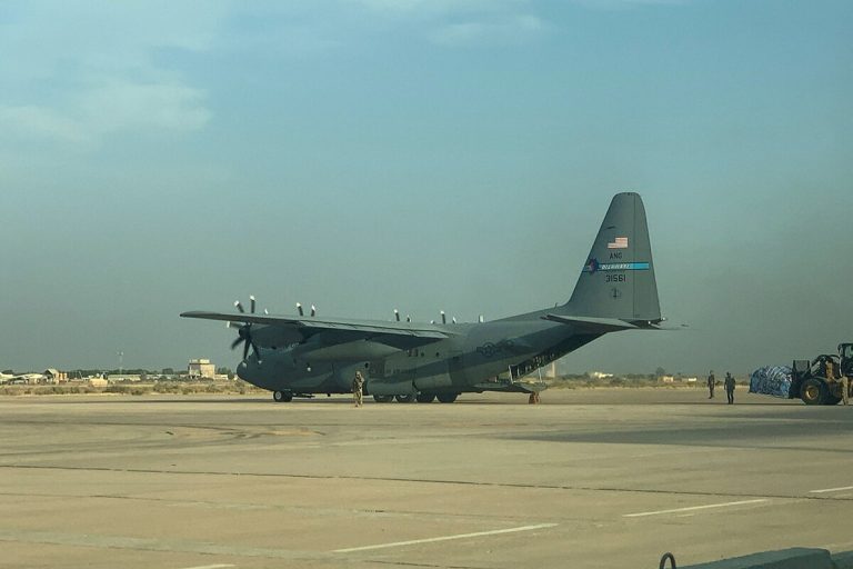 US Air National Guard C-130 Hercules transport aircraft parked on a desert runway tarmac.
