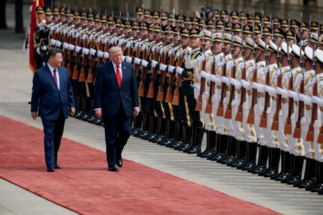 Xi Jinping and Donald Trump walking along a red carpet past a military honor guard.