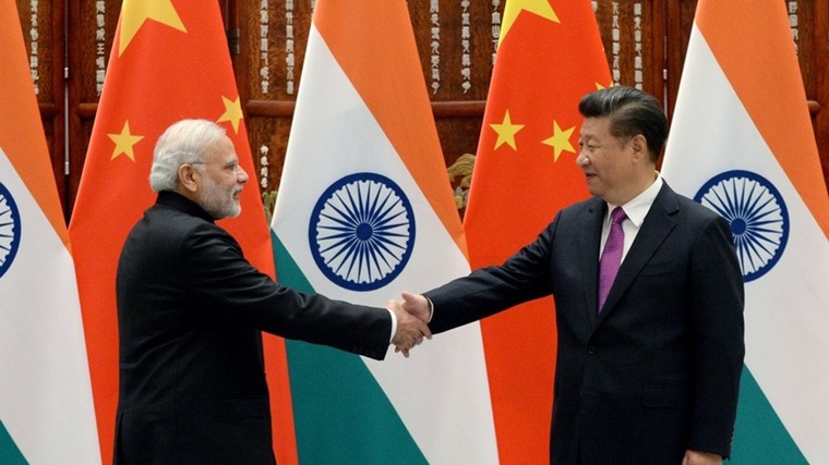 Indian Prime Minister Narendra Modi shaking hands with Chinese President Xi Jinping in front of national flags.