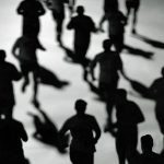 High-angle black and white silhouette of multiple runners moving together.