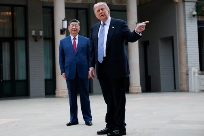 Donald Trump gesturing while standing alongside Xi Jinping outdoors.