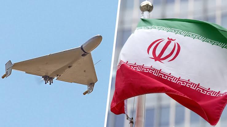 Iranian Shahed kamikaze drone flying against a blue sky alongside the national flag of Iran.