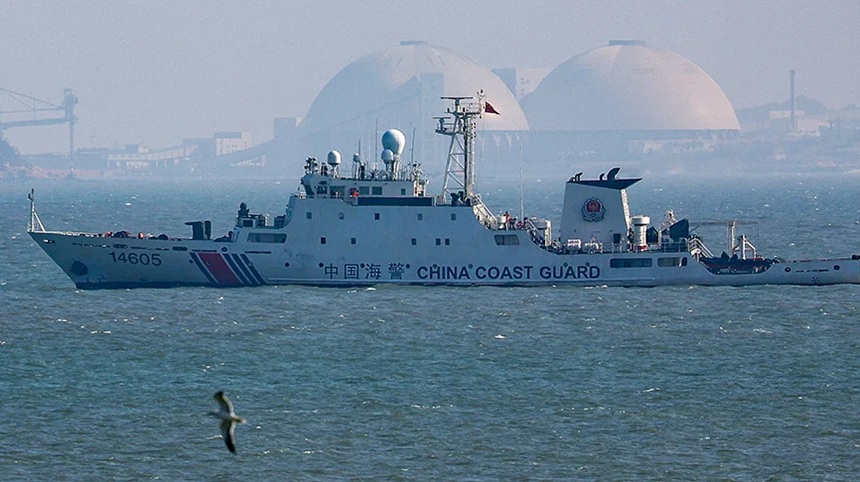 China Coast Guard patrol vessel sailing in open water with industrial domes in the background